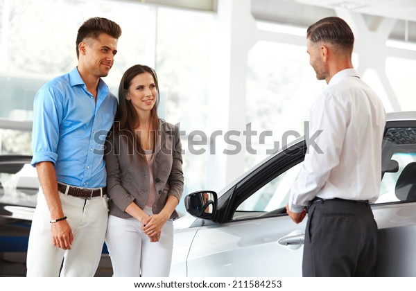 Car Showroom. Young Couple Buying a New Car\
at Dealership.
