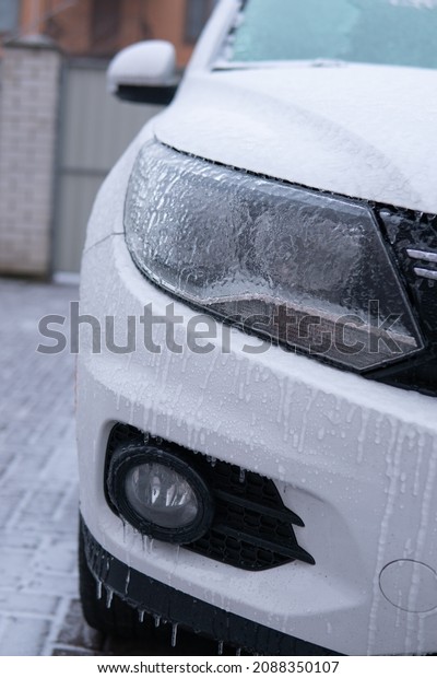 Car side\
mirror covered with ice . Frosty patterns on a completely covered\
car Windshield Frozen car winter driving . headlights with icicles\
and snow in winter season\
scraping