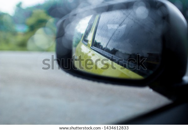Car side mirror glass with water
droplets from rain - driver's side rear view on rainy
day