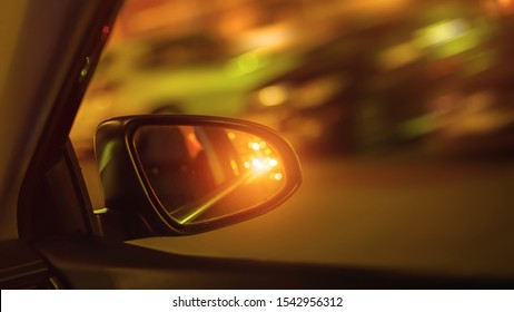 Car Side Mirror And Traffic Light From Vehicle Headlights At Night