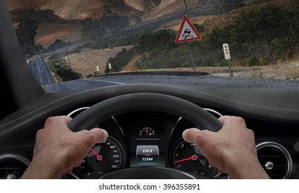 Car Slipping On A Road In The Rain. Alongside The Road Is A Sign For Slippery Road. Rain Splashed Windshield.