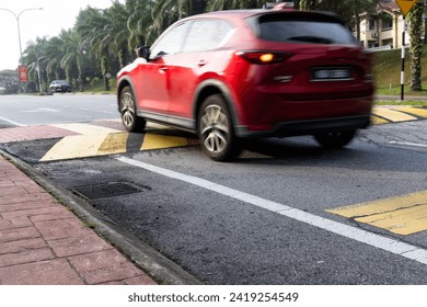 Car slowing down at speed bump or road hump painted in yellow and black stripe. Motion blur intended.