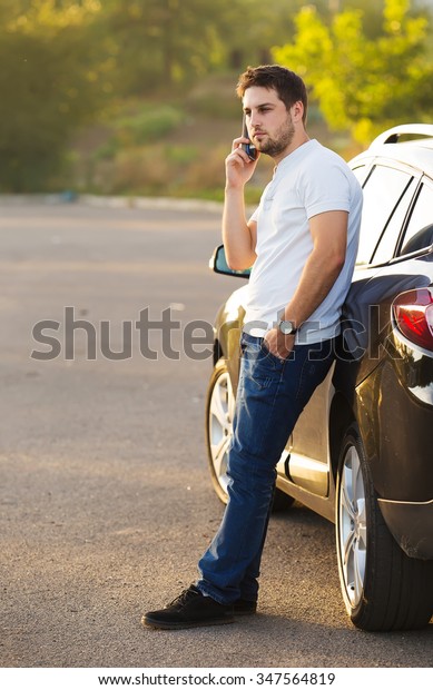 Car and smartphone\
app concept - man texting sms on phone. Driving young male adult\
using apps for travel or gps navigation help or reading news and\
texts using internet