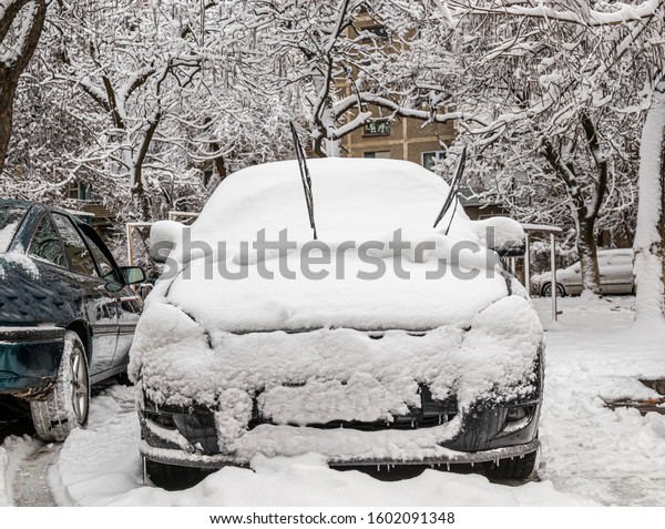 Car in the snow in\
the yard in the city