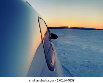 Car In A Snowy Field. Sunset