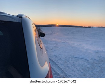 Car In A Snowy Field. Sunset