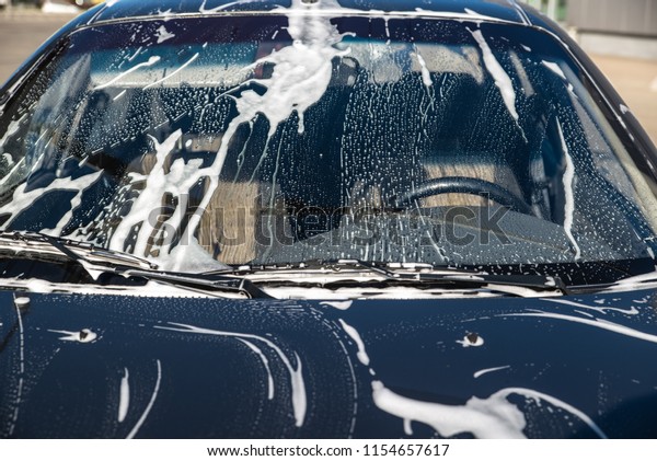 car in soap at\
carwash service. windshield