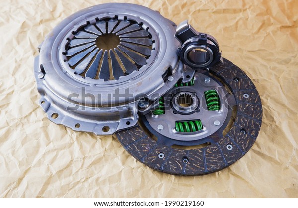 Car spare parts. Car clutch kit. Clutch\
disc, basket and clutch bearing. Car repair kit clutch manual\
gearbox on a background of craft\
paper.