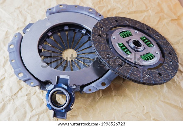 Car spare parts. Car clutch kit. Clutch\
disc, basket and clutch bearing. Car repair kit clutch manual\
gearbox on a background of craft\
paper.