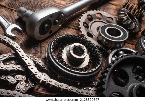 Car spare parts, gear wheels and wrenches\
on the wooden workbench close up\
background.