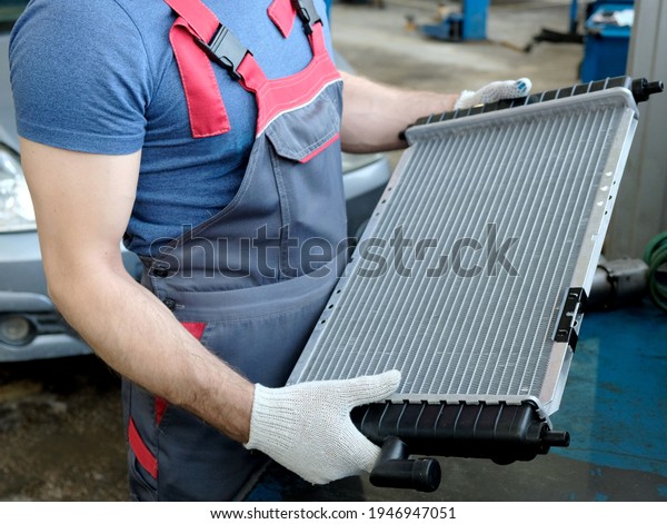 Car spare parts. In the hands of a\
car mechanic, a new automobile radiator of the engine cooling\
system. Repair and maintenance in the service\
center.