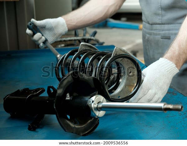 Car spare\
parts.The mechanic performs the work of replacing the spring and\
shock absorber of the front suspension strut of the car.Repair and\
maintenance in a car service\
station.