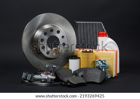 Car spare parts on a dark background. Brake discs, suspension arms and filters on a black background.