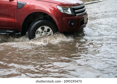 Car splashes through a large puddle on a flooded street - Shutterstock ID 1095195473