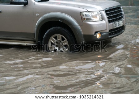Car splashes through a large puddle on a flooded street