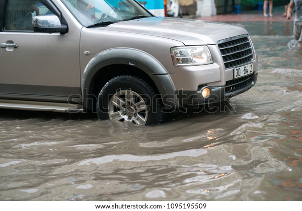 Car\
splashes through a large puddle on a flooded\
street