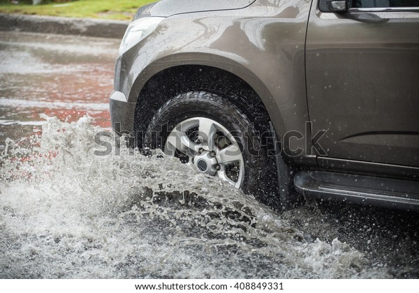 Car\
splashes through a large puddle on a flooded street\
