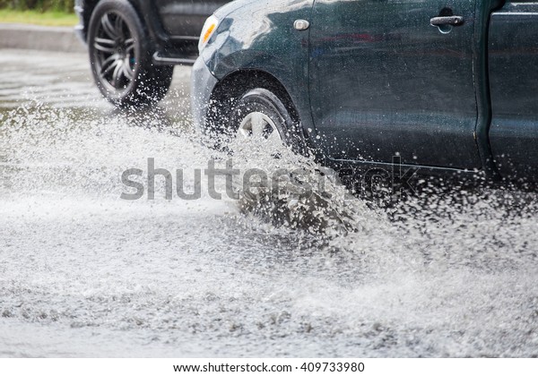 Car\
splashes through a large puddle on a flooded street\
