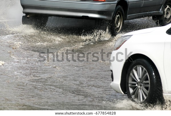 Car\
splashes through a large puddle on a flooded street. Motion car,\
rain, big puddle of water spray from the\
wheels