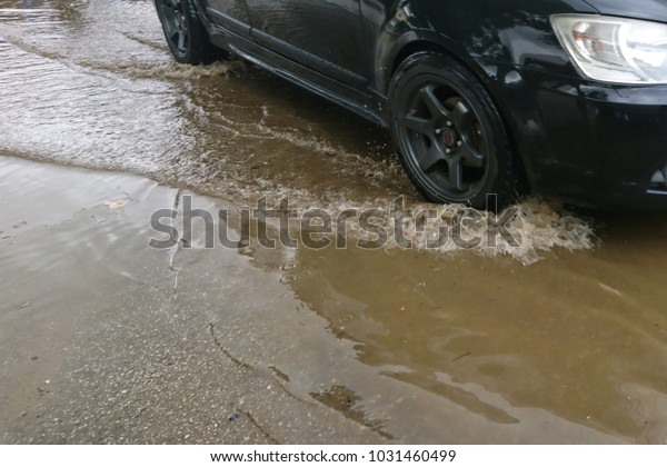 Car\
splashes trough water on a partly flooded\
road.\
\
