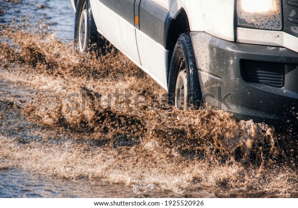 A car sprays mud in a dirt\
road