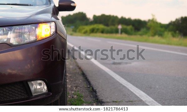 The car stands\
with the emergency gang switch on near the highway and cars pass\
by. Car breakdown. Forced\
stop