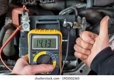 Car starter battery voltage measured with multimeter. Voltage above 14 volts as the alternator is charging the battery. Electric system working well. - Shutterstock ID 1903502365