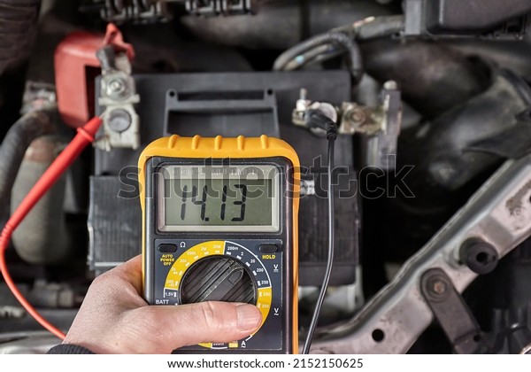 Car starter battery voltage measured with\
multimeter. Voltage above 14 volts as the alternator is charging\
the battery. Electric system working\
well.