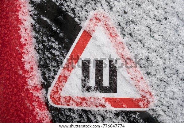 Car sticker on the rear snow-covered glass of the\
car warning drivers that the car is fitted with wheels with studded\
rubber
