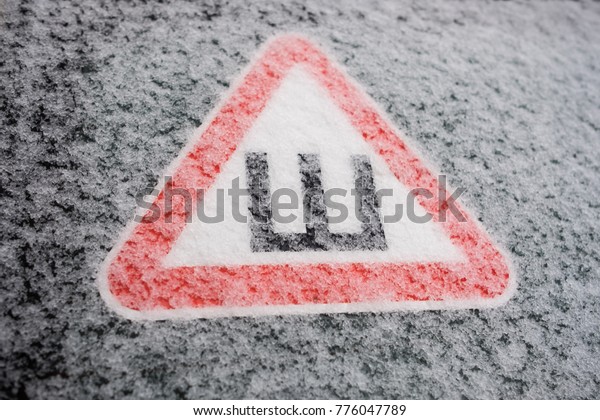 Car sticker on the rear snow-covered glass of the\
car warning drivers that the car is fitted with wheels with studded\
rubber