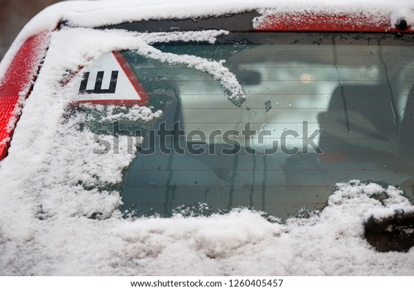 A car sticker with a Russian letter meaning spikes\
on the rear snow-covered glass of the car warns drivers that the\
car is equipped with studded wheels. Safe movement on snowy\
roads