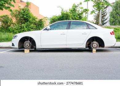 Car With Stolen Wheels. White Vehicle Left On Wooden Bricks.