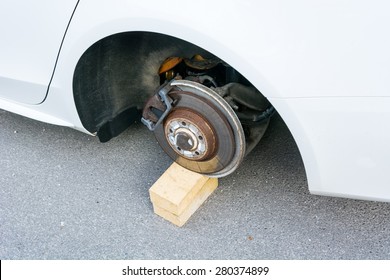 Car With Stolen Wheels. White Vehicle Left On Wooden Bricks.