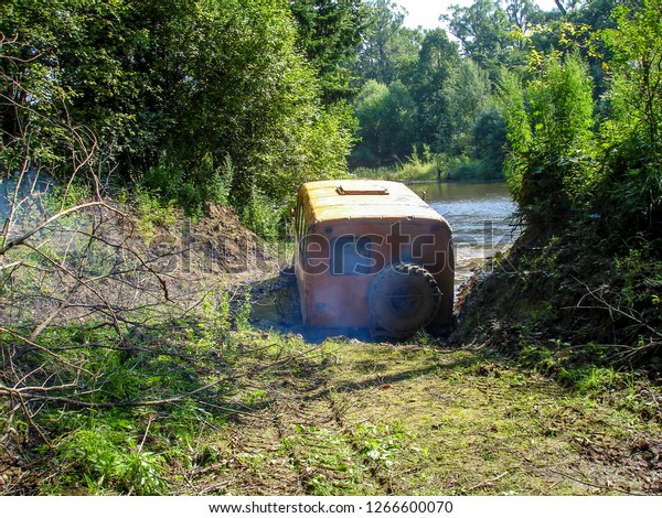 The car was stuck in a mud puddle.\
Crew bus crossing the river in the taiga. Extreme\
travel
