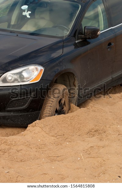 Car stuck in the sand.\
A black passenger car stalled on a sandy surface. Car wheels in a\
sand pit.