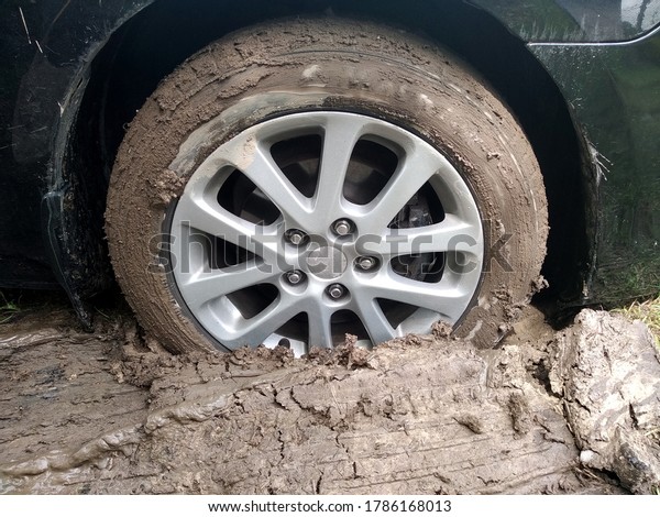 The car is stuck\
with a wheel in deep mud.