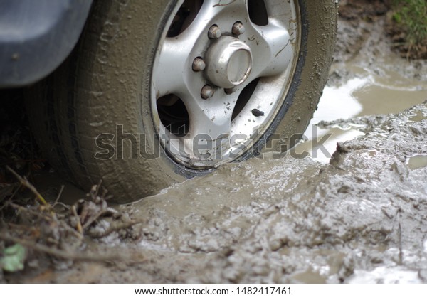 Car\
stuck, car wheel in a dirty puddle, rough\
terrain.
