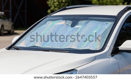 A car with a sun visor on the windshield. The visor is made of a reflective material that is designed to block the sun's rays