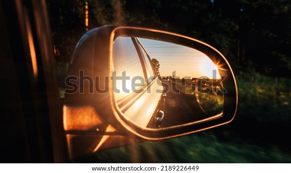 Car sunset road mirror.\
Summer sun, highway car road reflection in mirror. Vacation trip\
concept