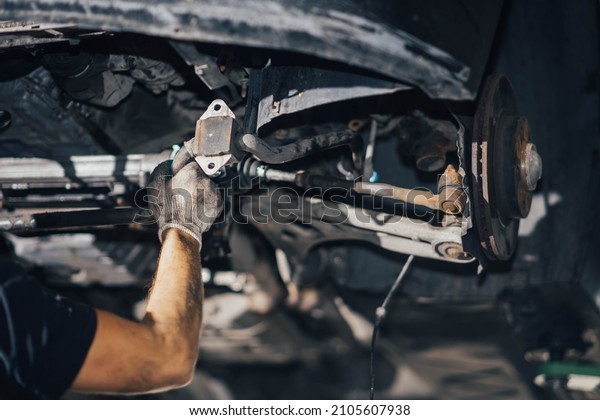 car suspension diagnostics, auto mechanic\
touches suspension arms and silent\
blocks