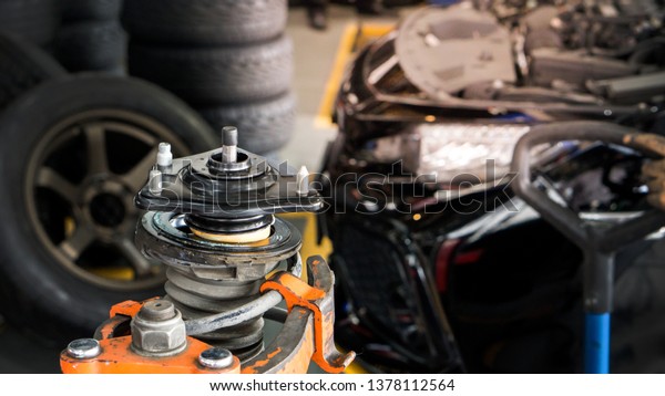 Car suspension and\
shock up absorber service concept - Blurred car suspension and\
shock up absorber service in service garage with flare light effect\
and copy space, 
