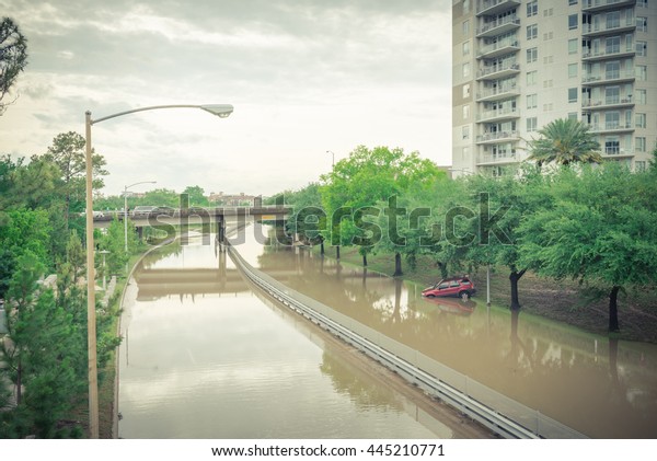 Car swamped by flood water near Buffalo Bayou Park\
in Houston, Texas. Flooded car under deep water on a heavy high\
water road. Disaster Motor Vehicle Insurance Claim Themed.Severe\
weather,vintage look