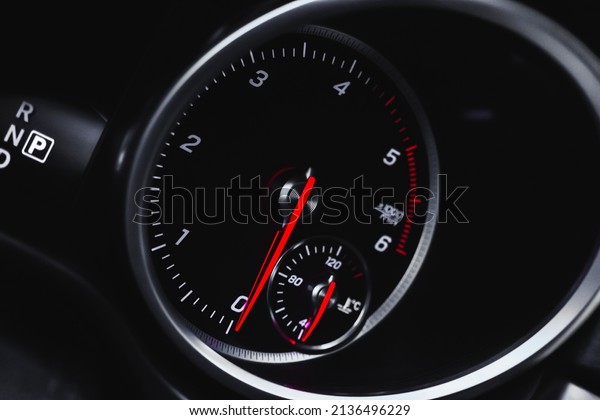 Car tachometer with glowing red\
indicators closeup view, of luxury dashboard in sport\
car