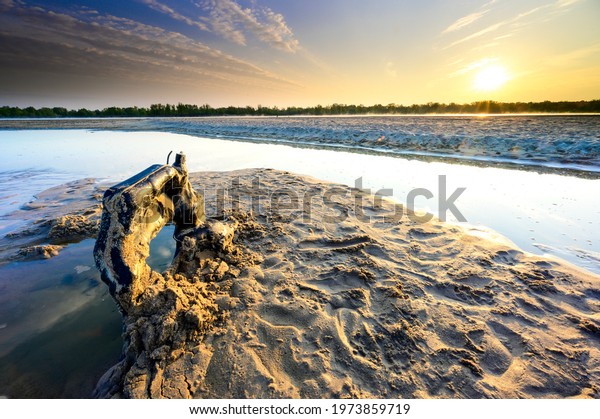 A car tank at the bottom of the drying\
up Vistula river bed in the spring at\
sunrise
