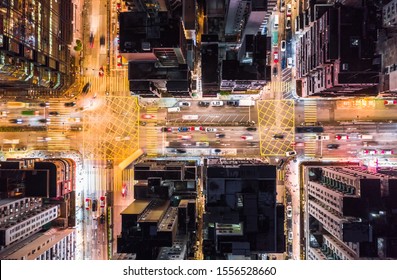 Car, taxi, and bus traffic on road intersection at night in Hong Kong downtown district, drone aerial top view. Street commuter, Asia city life, or public transportation concept