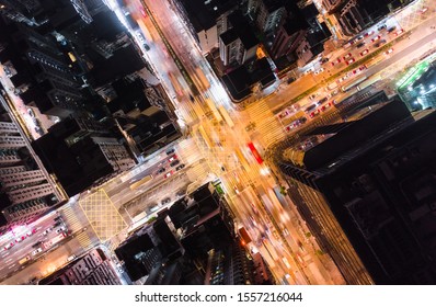 Car, Taxi, And Bus Traffic On Road Intersection At Night In Hong Kong Downtown District, Drone Aerial Top View. Street Commuter, Asia City Life, Or Public Transportation Concept