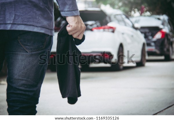 Car\
theft concept : Anonymous man holds face mask prepared to cause car\
thieves parked along the way : Blurred\
background
