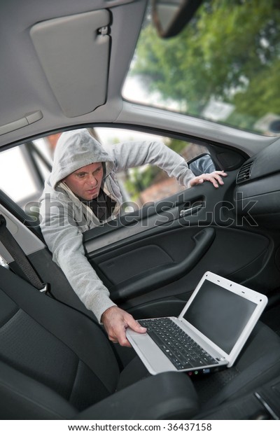 Car\
theft - a laptop being stolen through the window of an unoccupied\
car.  Shallow depth of field with focus on\
criminal.