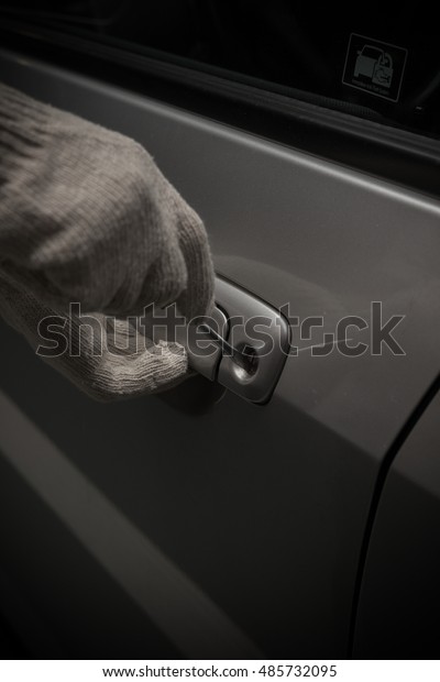 car thief with glove trying to open a vehicle door\
by screw driver