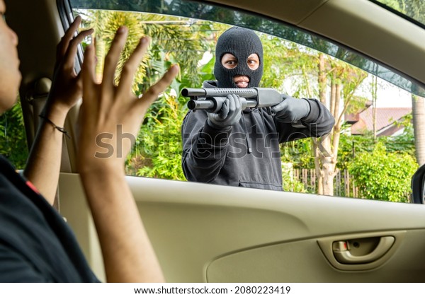 Car thief man pointing a shotgun at the driver on
the street